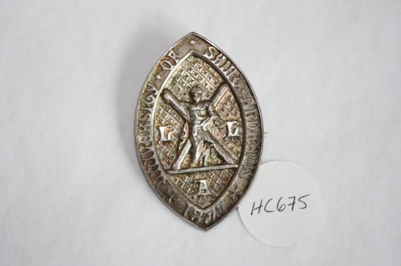 Almond-shaped badge with a relief of St Andrews.