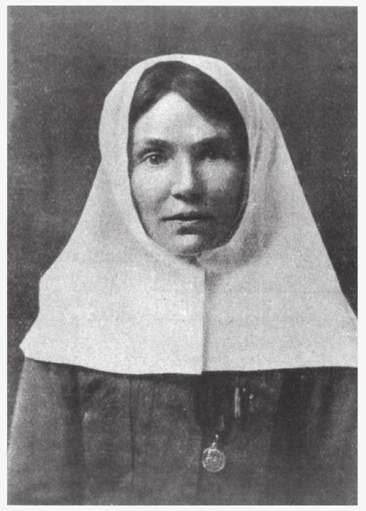 A woman with a white cloth over her head, wearing a large tunic.