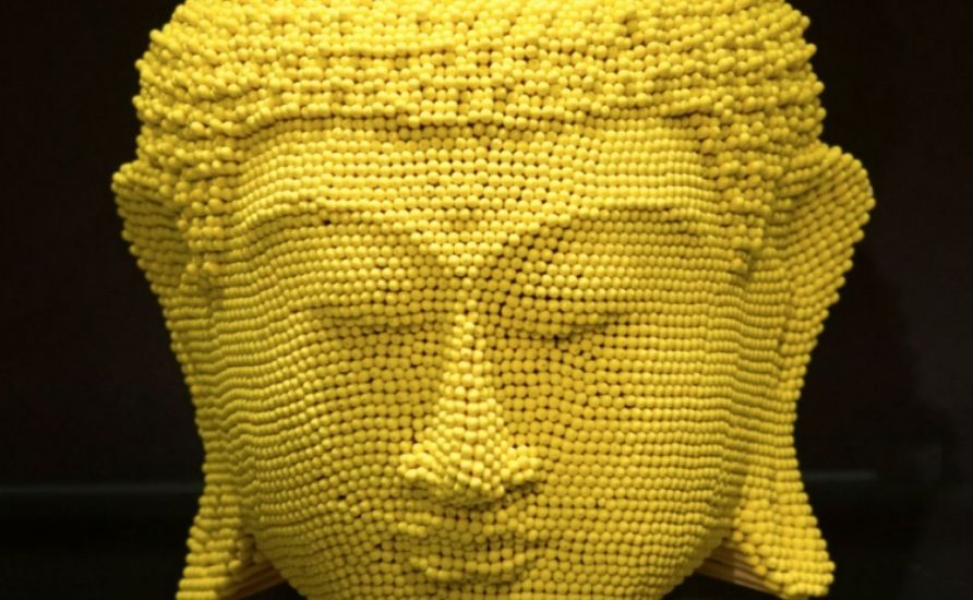 Yellow buddha head made of matches.