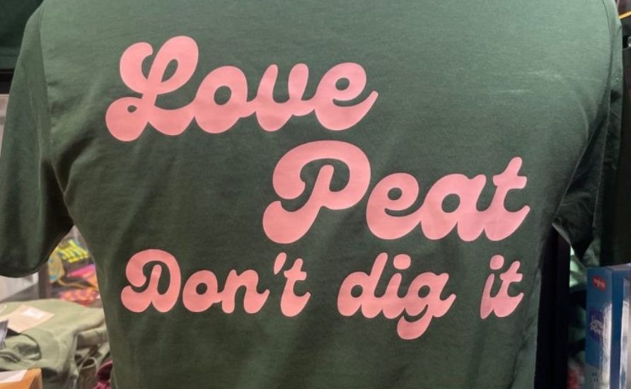 Back of a green t-shirt with the slogan: "Love Peat, don't dig it"